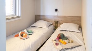 A room with two beds, a window, and built-in shelves. - ZEcamping 3* piscine chauffée locatif TV LV BBQ 33m2 6 pers (Martigues)