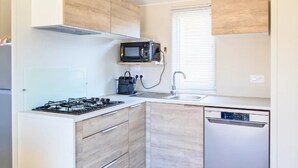 A compact kitchen with a gas stove, microwave, sink, and dishwasher. - ZEcamping 3* piscine chauffée locatif TV LV BBQ 33m2 6 pers (Martigues)