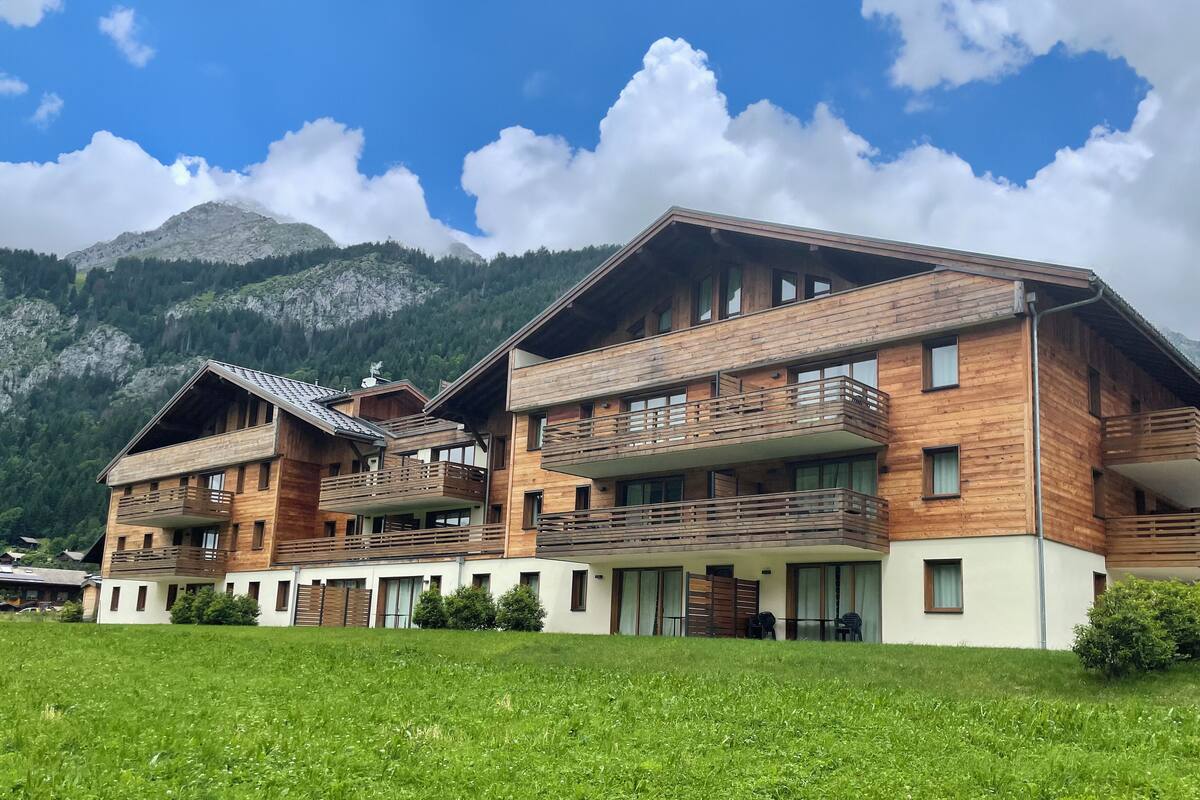 A modern wooden building with multiple balconies and a view of mountains.