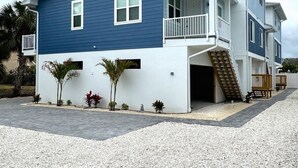A two-story building with a balcony on the second floor, a staircase leading to the entrance, and a small garden area with plants. - 3BR Gulf Getaway | Elevator, Pool, Walk to IRB (Indian Rocks Beach)