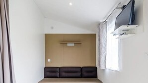 Une petite pièce moderne, avec un canapé, une petite table et un téléviseur fixé au mur.