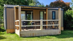Une cabane en bois avec une terrasse, une table et des chaises.