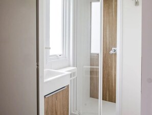 A bathroom with a white sink, a mirror, and a wooden door. - ZEcamping 4* piscine couverte locatif TV 24m2 (Pressignac)