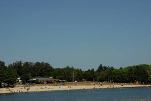 Een strand met mensen, parasols en een beschaduwd gedeelte.