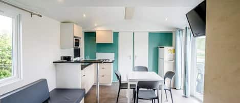 Un espacio habitable compacto con kitchenette, comedor y zona de estar.