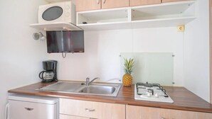 Eine kompakte Küche mit Mikrowelle, Herd, Kaffeemaschine und einer Ananas auf der Arbeitsplatte.