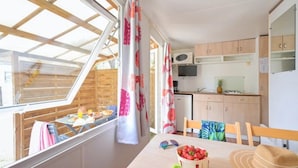 Eine kompakte Küche mit Holzschränken, einer Mikrowelle und einer kleinen Essecke mit Tisch und Stühlen.