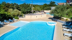 Piscina con sillas de descanso y zona de hidromasaje rodeada de follaje.