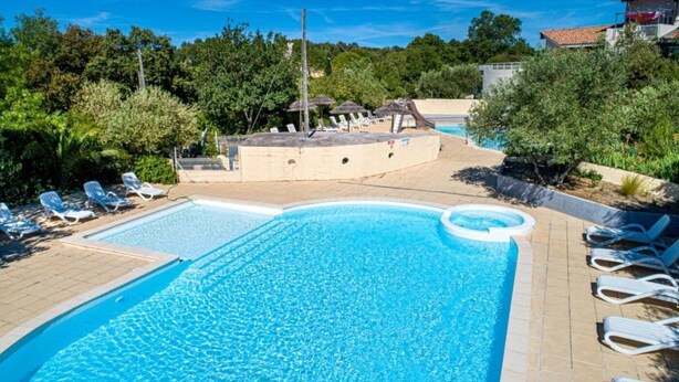 A swimming pool with lounge chairs and a hot tub area surrounded by greenery. - ZEcamping 3 étoiles familial toboggans locatif TV clim 26m2 4 pers (Sussargues)