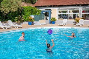 Une piscine avec des chaises longues et, au fond, un bâtiment dont le toit est recouvert de tuiles.