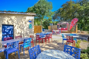 Un espace extérieur aménagé avec des tables et des chaises, un stand de restauration et un bâtiment avec une porte bleue.