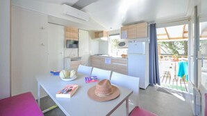 Une cuisine compacte dotée d’appareils électroménagers modernes, un coin repas avec une table et des chaises, et une vue sur l’extérieur.