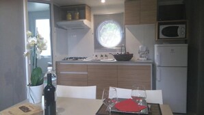 A compact kitchen with a dining table, chairs, a microwave, and a stove.