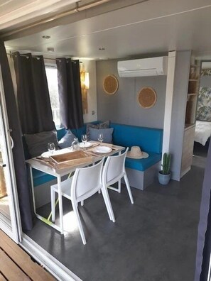 Un espace de vie compact comprenant un coin repas, un canapé bleu et une petite table mise pour deux personnes.
