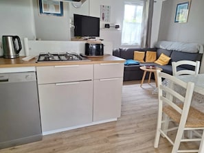 A compact kitchen with a gas stove, a coffee maker, and a dishwasher.