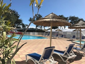A poolside area with lounge chairs and thatched umbrellas.