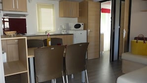 Una cucina compatta con mobili in legno, un forno a microonde e un'area pranzo con sedie in vimini.