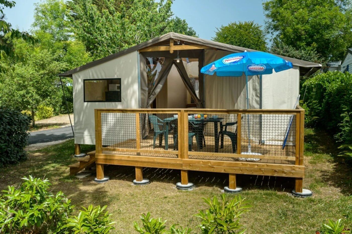 En lille, etplans hytte med en indhegnet terrasse og et bord med stole udendørs.