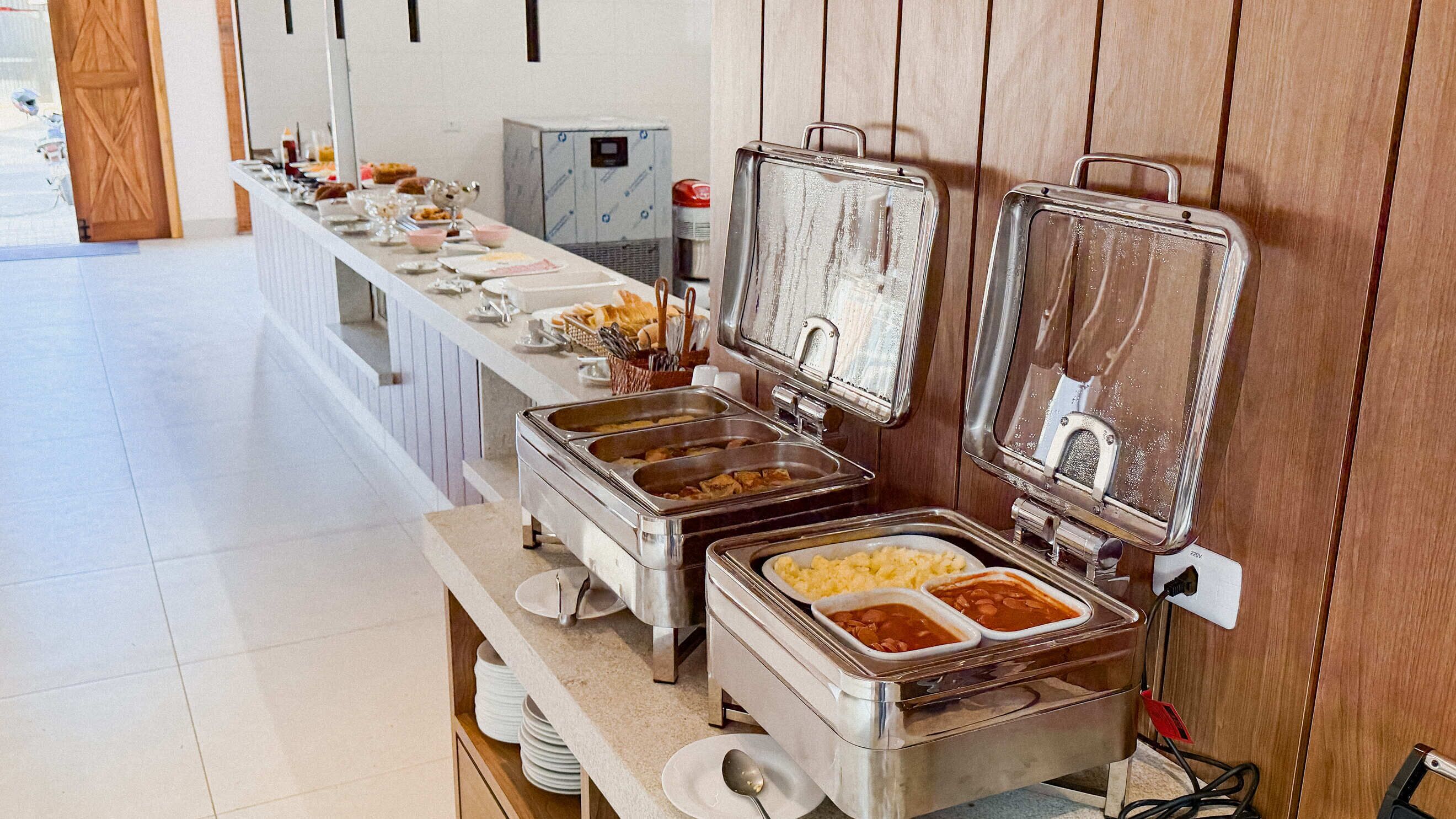 A buffet setup with multiple food stations, a coffee machine, and a refrigerator.