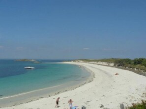 A beach with clear turquoise water, a sandy shore, and a few people.