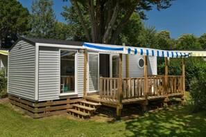 A mobile home with a covered porch and a small deck.