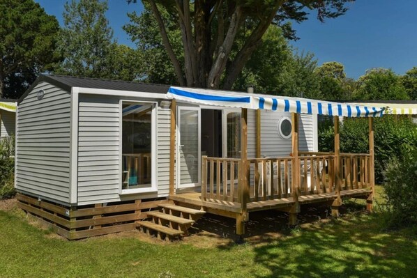 A mobile home with a covered porch and a small deck.