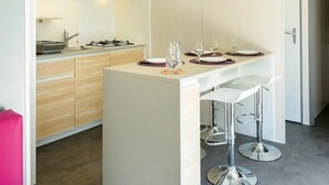 Ett modernt kök med en central köksö, barstolar och en ljus taklampa.