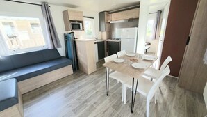 Ein kompakter Wohnraum mit Küchenzeile, einem Essbereich und einer Sitzecke inklusive Sofa und Tisch für vier Personen.