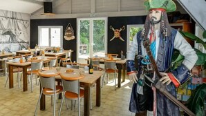 Ein Restaurant mit Holztischen und -stühlen, einer großen Piratenstatue und einem Wandgemälde.