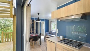 A modern kitchen with a gas stove, wooden cabinets, and a dining area with a table and chairs.