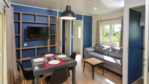 A modern living room with a dining area, a sofa, and a TV mounted on the wall.