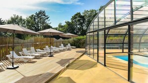 A sunlit outdoor area with wooden deck, white lounge chairs, and umbrellas.