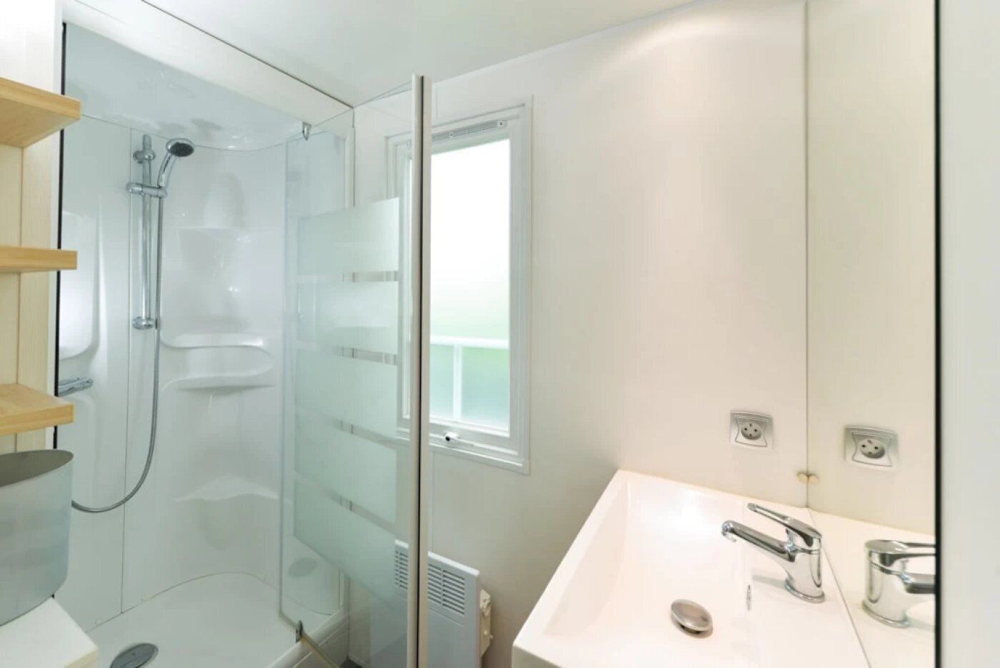 A modern bathroom with a glass-enclosed shower, a white sink with chrome fixtures, and a large mirror.