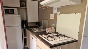 Eine kleine Küchenzeile mit Mikrowelle, Kühlschrank, Herd und Spüle.