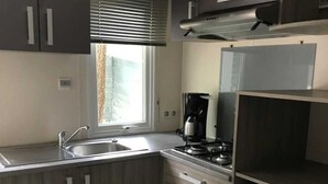 Een kleine keuken met een ingebouwd gasfornuis, een koffiezetapparaat en een minibar.
