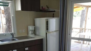 A compact kitchen with dark cabinets, a white refrigerator, and a coffee maker.