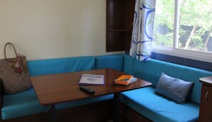 Een kamer met een blauwe bank, een houten tafel, een afstandsbediening, een boek en een handtas.