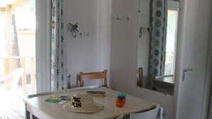 A dining area with a table, chairs, and a ceiling light. - ZEcamping 3* toboggans piscine chiens acceptés locatif 6 pers (Peynier)
