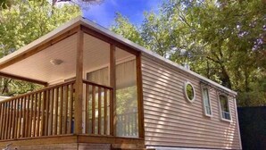 A mobile home with a wooden deck and a covered porch. - ZEcamping 3* toboggans piscine pet friendly locatif 4 pers (Peynier)