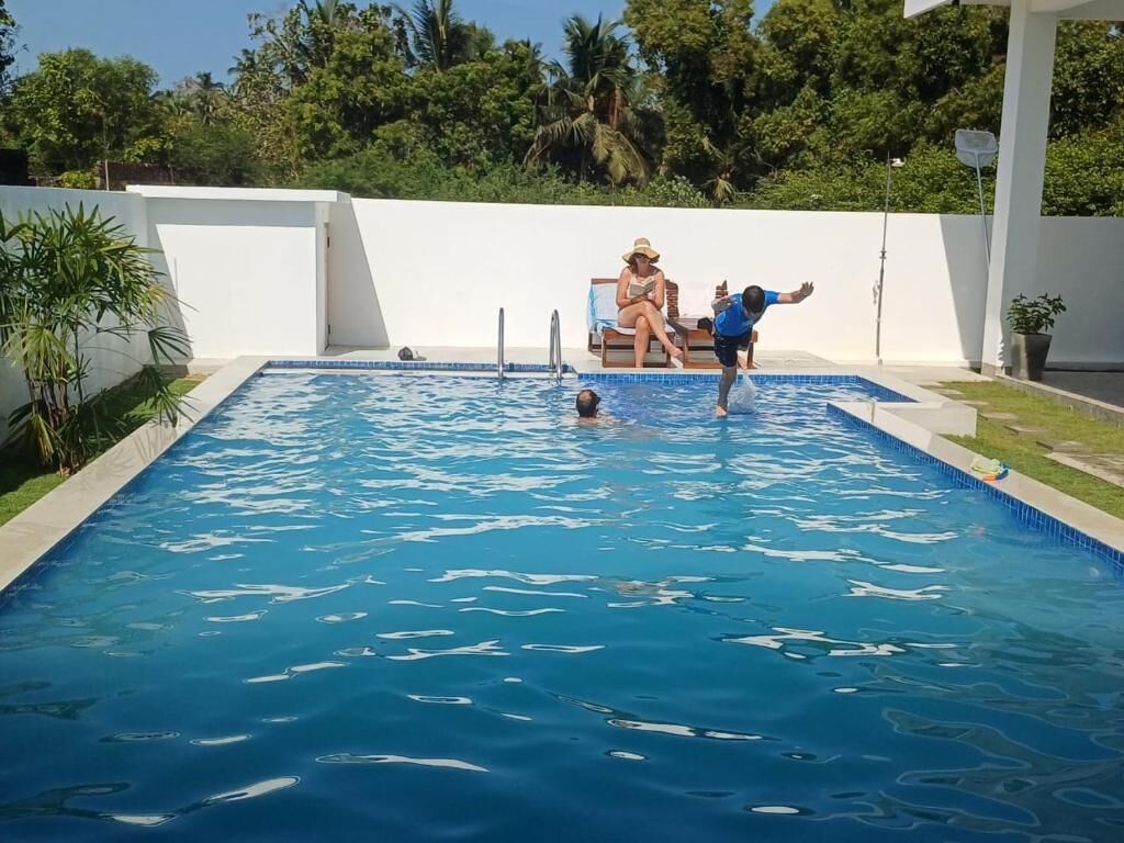 A swimming pool with a white wall and a person in the water.