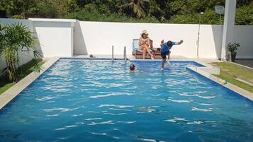 A swimming pool with a white wall and a person in the water.