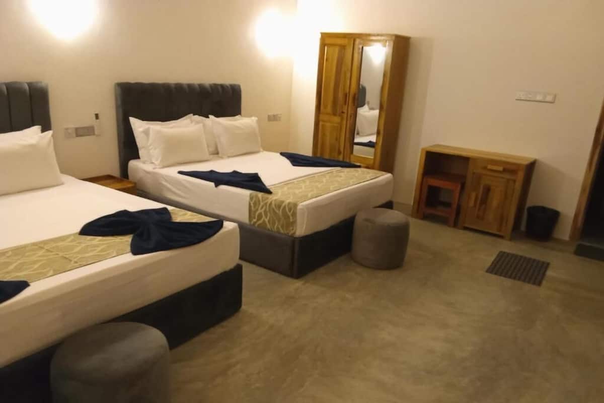 Ein Hotelzimmer mit zwei Betten, einem Kleiderschrank, einem kleinen Tisch und einer Bank.