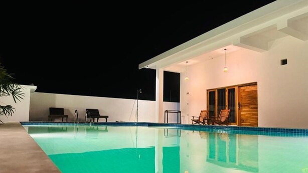 A swimming pool with lounge chairs and a covered seating area.