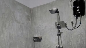 A bathroom with a toilet, a shower, and a wall-mounted control panel.