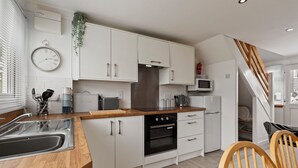 Eine moderne Küche mit weißen Schränken, einer Holz Arbeitsplatte, einer Edelstahl-Spüle und einem eingebauten Backofen.