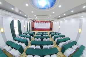 A conference room with rows of tables and chairs, a stage with a red carpet, and a large circular ceiling feature. - Huanyu Grand Hotel (Yishui Dongfang Shopping Center Chang'an South Road) (Yishui)