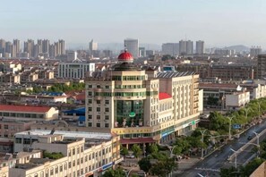 A cityscape with a prominent building featuring a red dome, surrounded by other buildings and a clear sky. - Huanyu Grand Hotel (Yishui Dongfang Shopping Center Chang'an South Road) (Yishui)