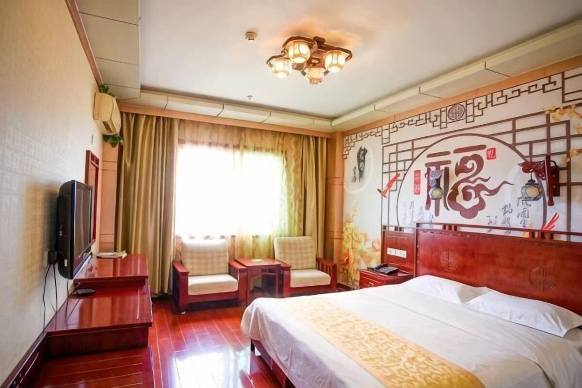 Une chambre d’hôtel comprenant un lit, deux chaises, un bureau, une télévision et un mur décoratif.