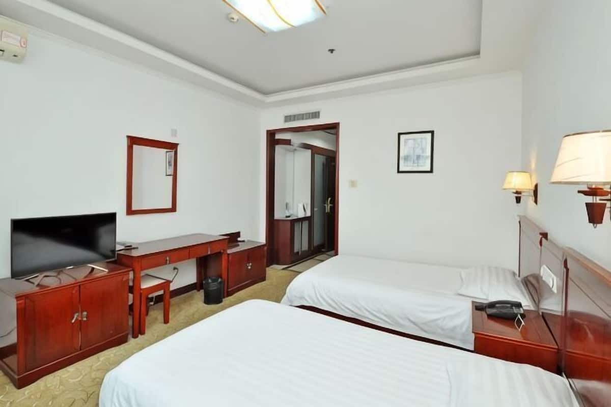 Une chambre d’hôtel avec deux lits, un bureau, une télévision et un miroir.