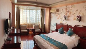 Una habitación de hotel con cama, televisión, escritorio y silla.